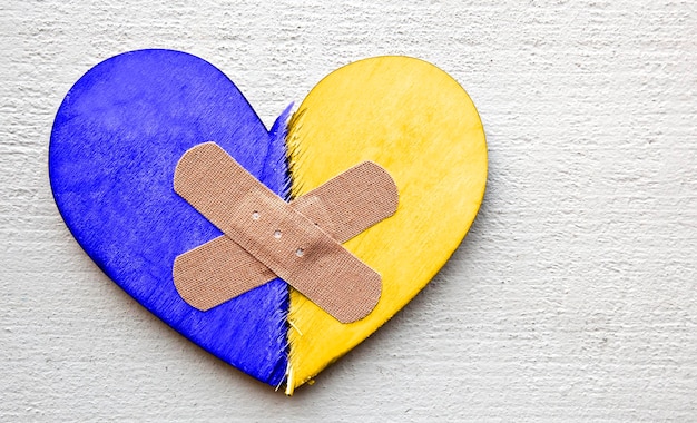 Deux parties de coeur en bois brisé aux couleurs du drapeau ukrainien collées par un patch