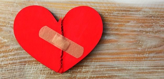 Deux parties de coeur en bois cassé rouge collées par un patch Concept du pardon renouvellement des relations et de la guérison