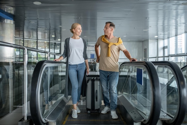 Deux passagers de l'aéroport d'âge moyen descendant de l'escalier mobile