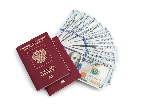 Deux passeports rouges et billets de cent dollars sur fond blanc.