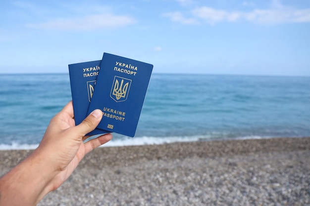 Deux passeports ukrainiens biométriques en main sur fond de bord de mer