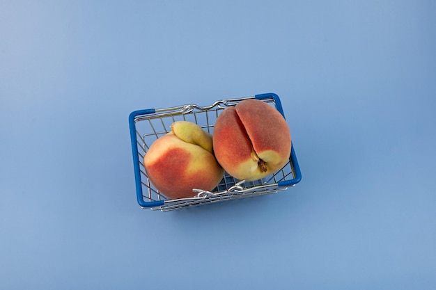 Deux pêches déformées dans le panier sur fond bleu. Fruits moches.