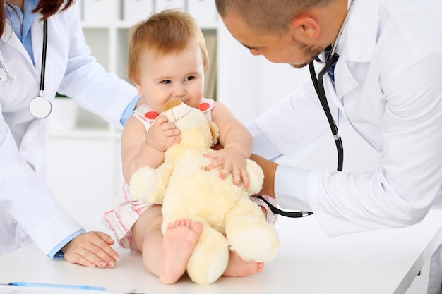 Deux pédiatres s'occupent d'un bébé à l'hôpital Une petite fille est examinée par un médecin avec un stéthoscope Assurance soins de santé et concept d'aide