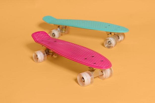 Deux penny skateboard rose et vert isolé sur espace jaune