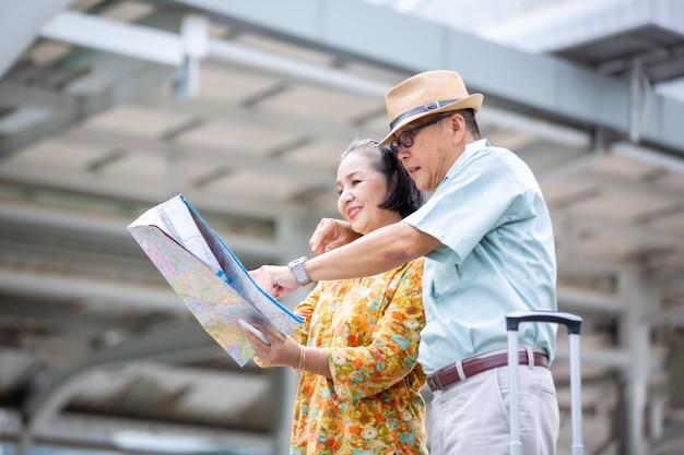 Deux Personnes âgées Asiatiques Voyageant Avec Carte Et Bagages Contre Bâtiment