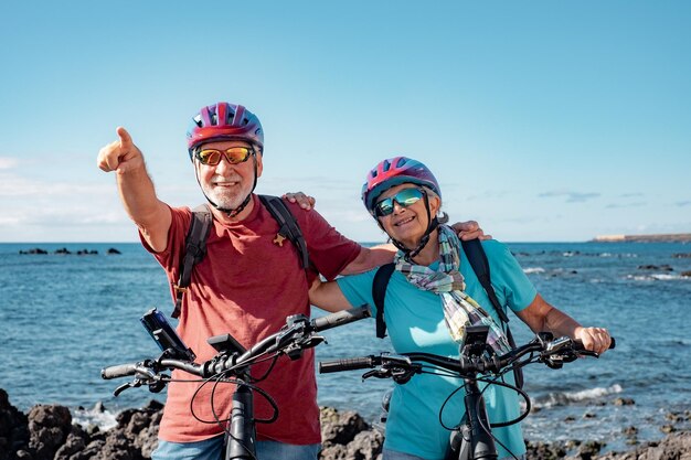 Photo deux personnes âgées heureuses qui aiment faire du vélo ensemble en mer mode de vie actif et sain