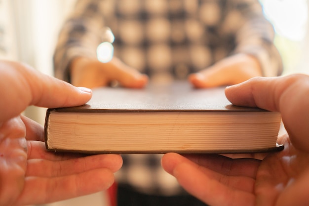 Deux personnes échangent le livre, transmettant le savoir aux jeunes générations