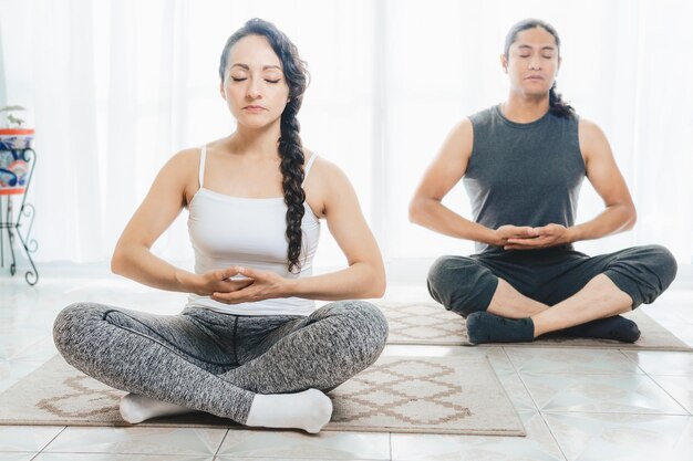 Deux personnes font du yoga à l'intérieur il y a beaucoup de lumière