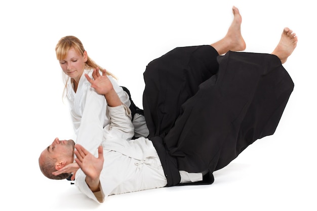 Deux personnes un homme et une femme pratiquent l'aïkido sur le tapis isolé sur fond blanc