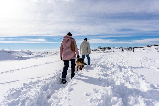 Deux personnes marchant avec leur chien à l'extérieur sur la neige en hiver