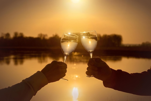 Deux personnes portant un toast avec des verres à vin sur un lac