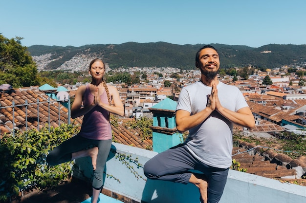 Deux personnes pratiquant le yoga et la méditation, un homme latino et une femme caucasienne.