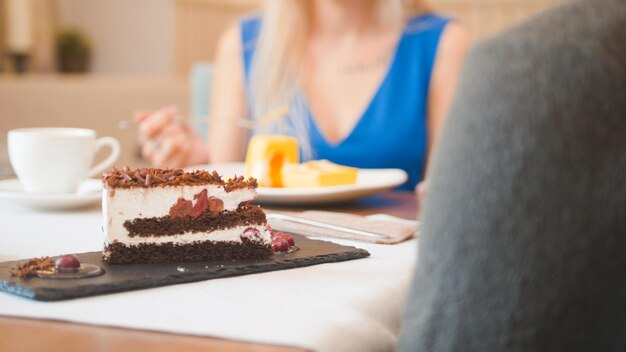 Deux personnes de race blanche dans le café appréciant les desserts et parlant de près