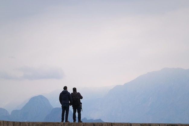 Deux personnes se tiennent sur le fond du ciel et de belles montagnes dans la brume et le brouillard