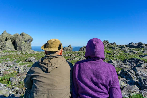 Deux personnes en vêtements de voyage sont assises dans le paysage de montagne