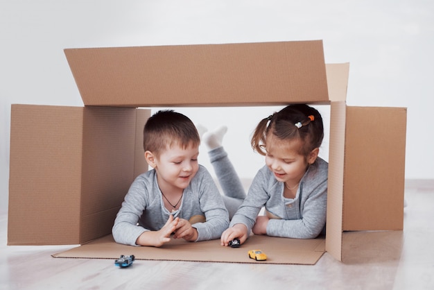 Deux un petit garçon et une fille jouant des petites voitures dans des cartons. photo. Les enfants s'amusent. Photo de concept. Les enfants s'amusent