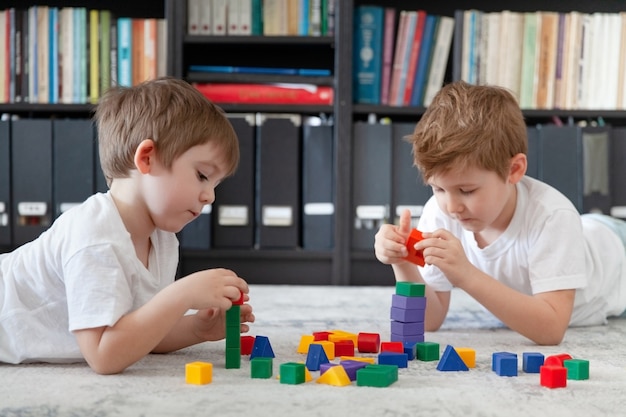 Deux petit garçon de race blanche jouant avec des jouets en bois matériaux Montessori