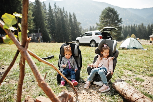 Deux petite fille assise au coin du feu en montagne. Météo de randonnée d'automne. Réchauffement et cuisson près de la flamme ensemble.