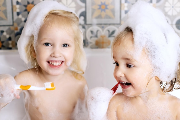 Deux petite fille se brosser les dents coin dans la salle de bain avec mousse de bain pour enfants soins personnels amusement en famille