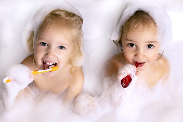 Deux petite fille se brosser les dents coin dans la salle de bain avec mousse de bain pour enfants soins personnels amusement en famille