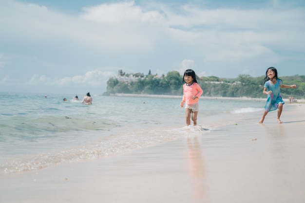 Deux petites asiatiques courir pour éviter les vagues