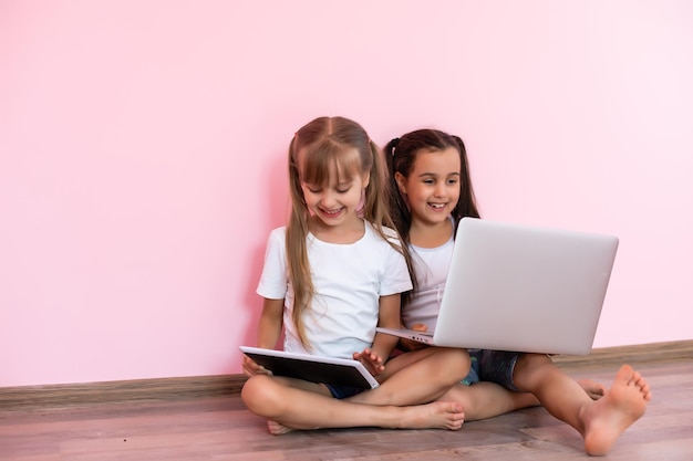 Deux petites filles assises devant un ordinateur portable et riant, gros plan, émotions positives, divertissement sur Internet pour les enfants