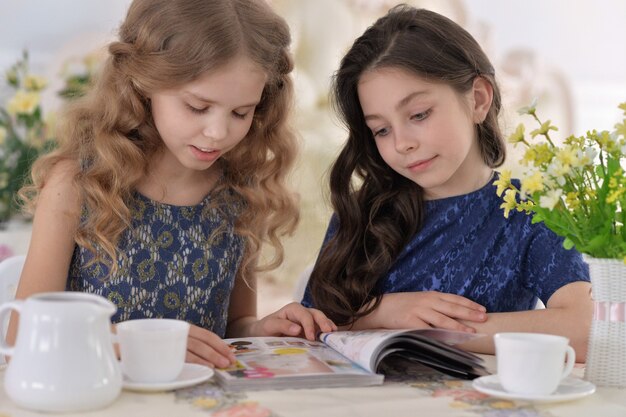 Deux petites filles buvant du thé et lisant un magazine