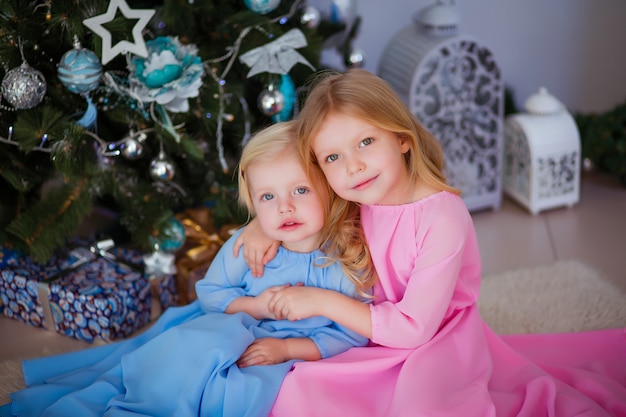 deux petites filles à côté de l'arbre de Noël