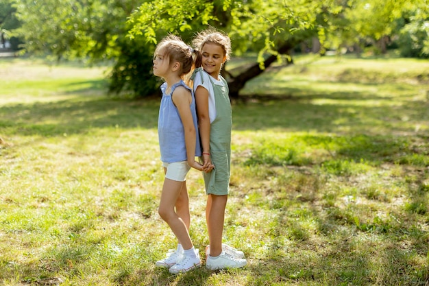 Deux petites filles debout dos à dos dans le parc