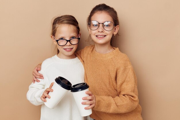 Deux petites filles drôles un verre avec une boisson fond beige