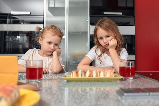 Deux petites filles frères et sœurs s'amusant et mangeant dans la cuisine à la maison avec de la nourriture japonaise