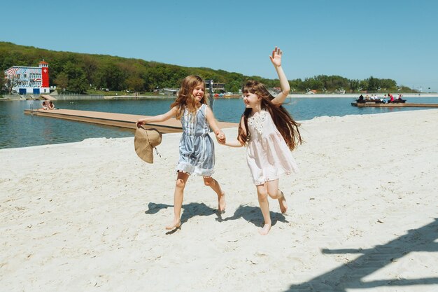 Deux petites filles heureuses courent gaiement et joyeusement le long de la plage se réjouissent et s'amusent