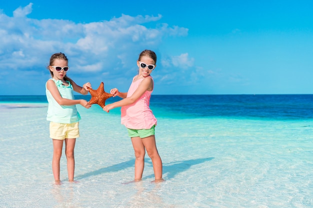 Deux petites filles heureuses s'amusent beaucoup sur une plage tropicale en jouant ensemble