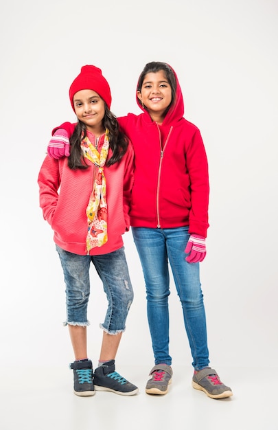 Deux petites filles indiennes dans des vêtements chauds debout sur fond blanc