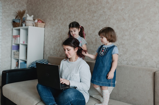 Deux petites filles jouent avec leur mère, se coiffent, se coiffent. Mère attentionnée