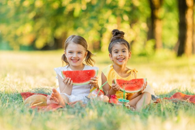 Deux petites filles mangeant de la pastèque dans le jardin Les enfants mangent des fruits à l'extérieur Les filles profitant de la pastèque