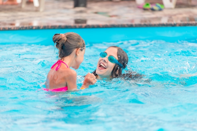 Deux petites filles mignonnes de soeurs nagent dans la piscine