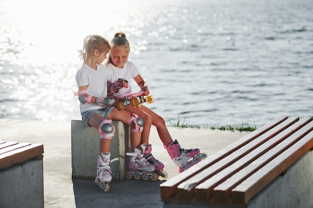 Deux petites filles avec des patins à roulettes à l'extérieur près du lac