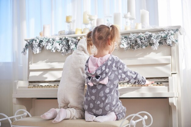 Deux petites filles en pyjama au piano le jour de Noël