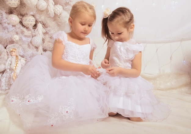 Deux petites filles en robes blanches près d'un arbre de Noël avec une décoration de nouvel an