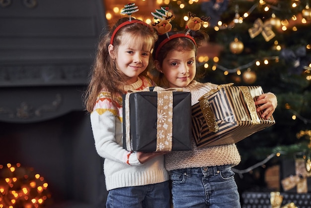 Deux petites filles s'amusent dans une chambre décorée de noël avec des coffrets cadeaux.