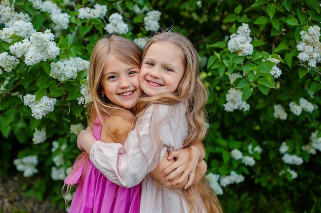 Deux petites filles s'embrassant devant un buisson de fleurs