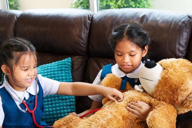 Deux petites filles sourient et jouent au docteur avec un stéthoscope.