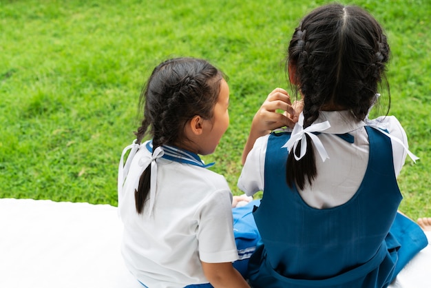 Deux petites soeurs asiatiques filles embrassant poste heureux en uniforme scolaire, concept de retour à l&#39;école