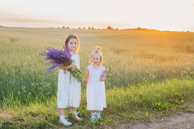 Deux petites soeurs avec des fleurs violettes en plein air