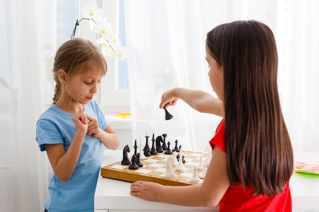 Deux petites soeurs jouant aux échecs à la maison