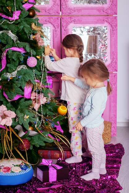 Deux Petites Soeurs En Pyjama Décorées D'un Sapin De Noël.