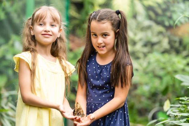 Deux petites sœurs tenant un papillon dans leurs mains. Enfants explorant la nature. Loisirs en famille avec des enfants en été.