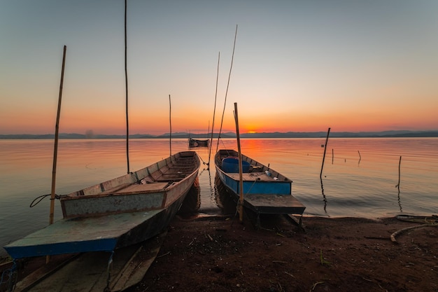 Deux petits bateaux amarrés au bord du lac. au coucher du soleil