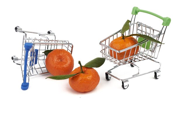 Deux petits chariots pour l'épicerie du supermarché et trois mandarines aux feuilles vertes isolées sur fond blanc.